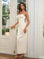 Woman in a long, ivory strapless satin gown with a sweetheart neckline, posing by a door.