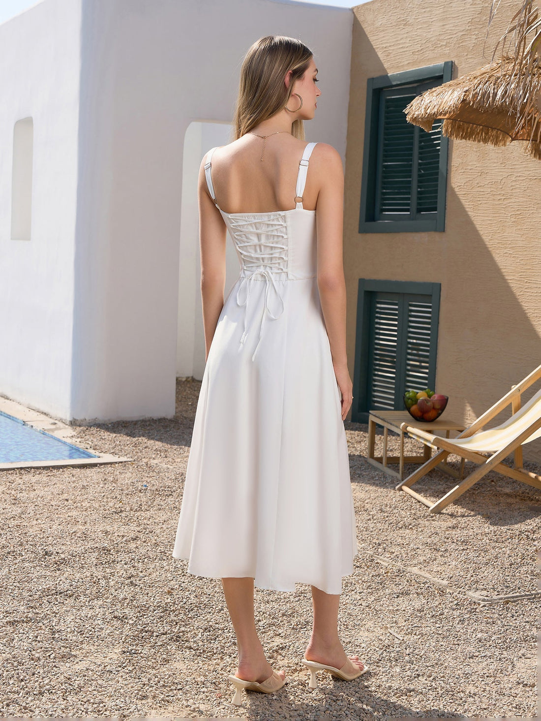 Woman wearing a white midi dress with spaghetti straps and a thigh-high slit