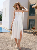 Woman in a white midi dress, straw hat, and straw bag