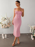 Woman wearing a pink crepe midi dress, holding her chest