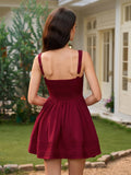 Rear view of a woman in a burgundy sleeveless fit and flare dress with a smocked back panel and pleated hem.