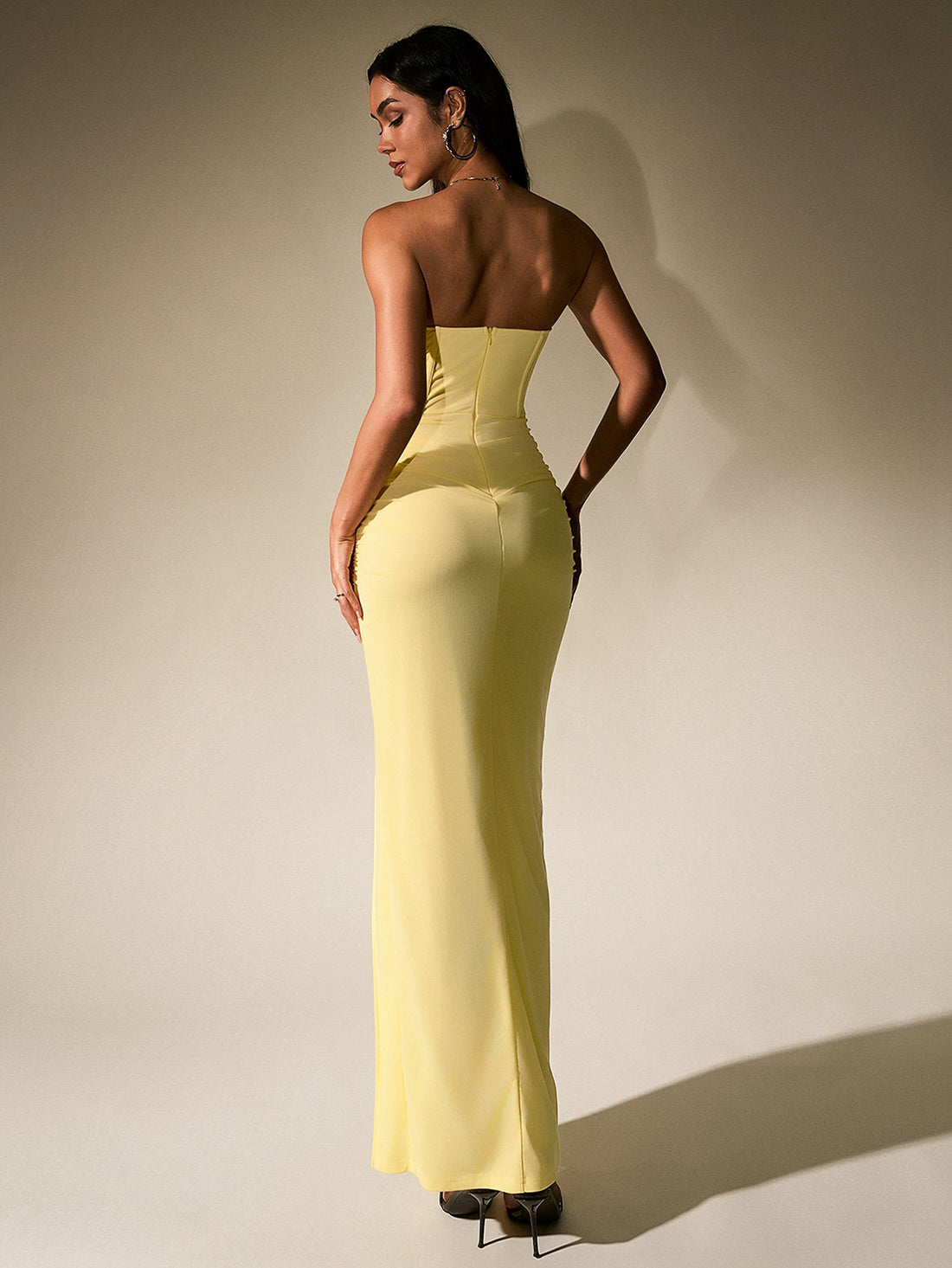 Woman wearing a strapless yellow chiffon gown with a sweetheart neckline and a high slit.