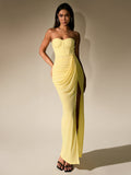 Full-length shot of a woman in a yellow ruched chiffon gown with a thigh-high slit.