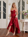 Woman wearing a red satin formal dress with a cowl neck and asymmetrical hemline