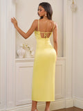 Rear view of a woman in a yellow satin sheath dress with spaghetti straps and a tie back.