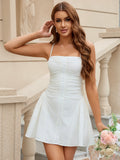 Woman in a white ruched dress with a pleated skirt holding flowers