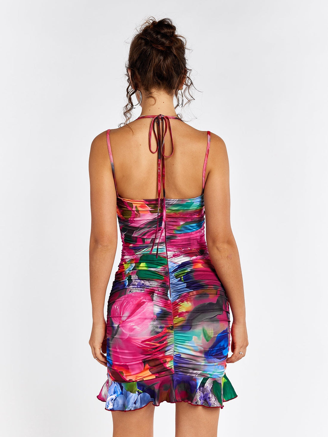 Woman wearing a colorful abstract floral print bodycon mini dress with ruching and a cut-out detail.