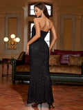 Woman wearing a black strapless sequined mermaid evening gown, back view