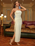 Woman posing in a cream strapless column maxi dress with a ruched bodice and high slit, showing the side view.