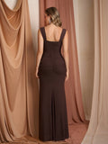 Back view of a woman in a brown ruched maxi dress with a high slit.