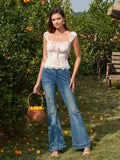 Woman holding a basket of oranges in a white floral print corset top and blue jeans