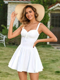 Woman wearing a white fit and flare mini dress and a straw hat.