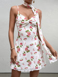 woman wearing a white sleeveless A-line dress with a red cherry print and a knot front detail