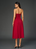 Rear view of a woman in a red strapless midi dress with a ruched bodice and full skirt