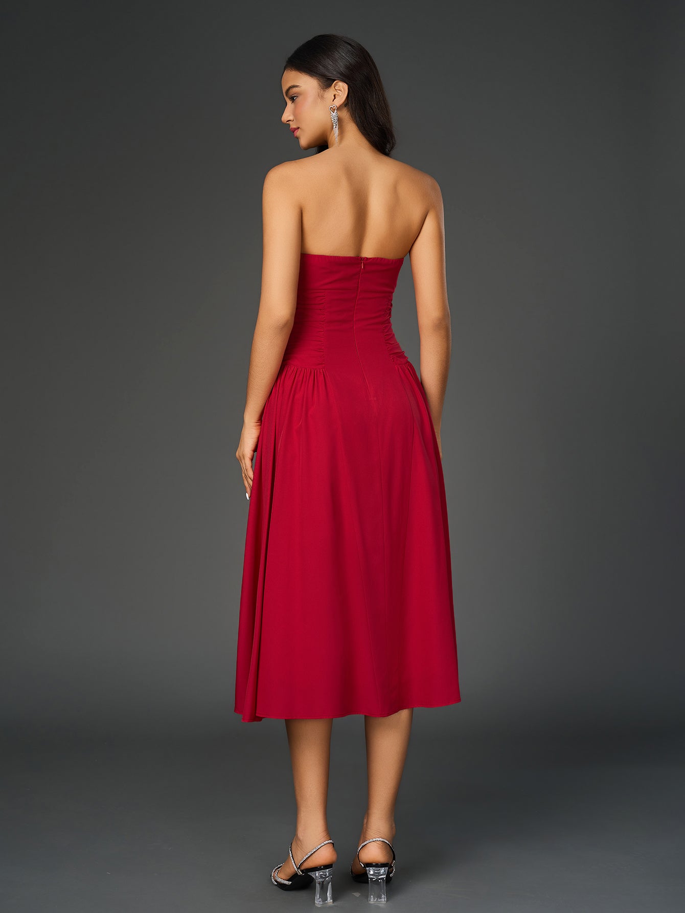 Rear view of a woman in a red strapless midi dress with a ruched bodice and full skirt