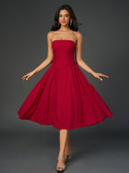 Woman wearing a red strapless midi dress with a ruched bodice and full skirt, posing with arms outstretched