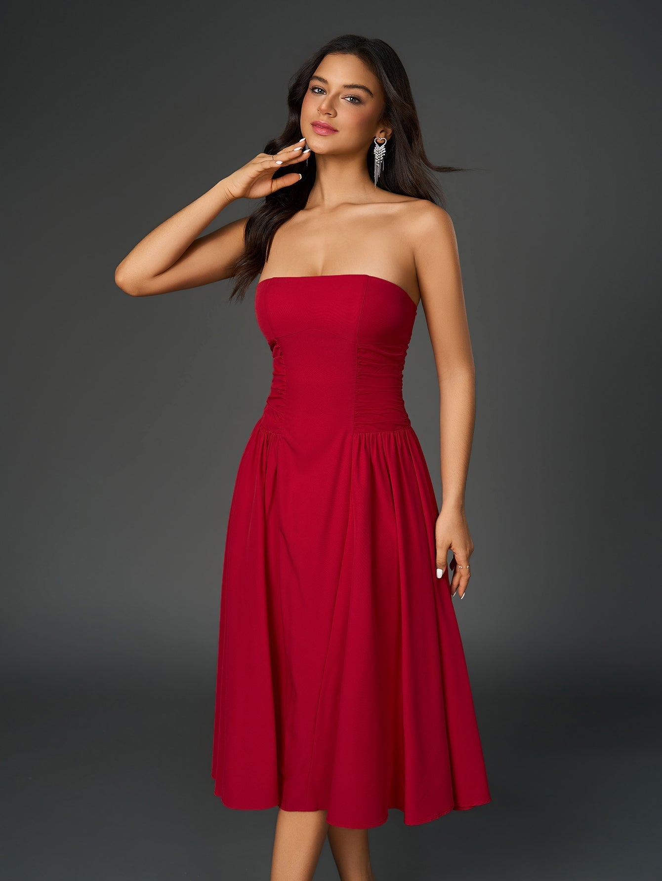 Woman in a red strapless midi dress with a ruched bodice and full skirt, touching her neck