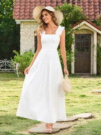 Woman wearing a white sleeveless midi dress with ruffled shoulder straps and a smocked bodice, standing in a garden.