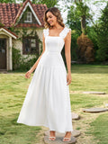 Full-length shot of a woman in a white midi dress with ruffled straps and a tiered skirt, posing outdoors.