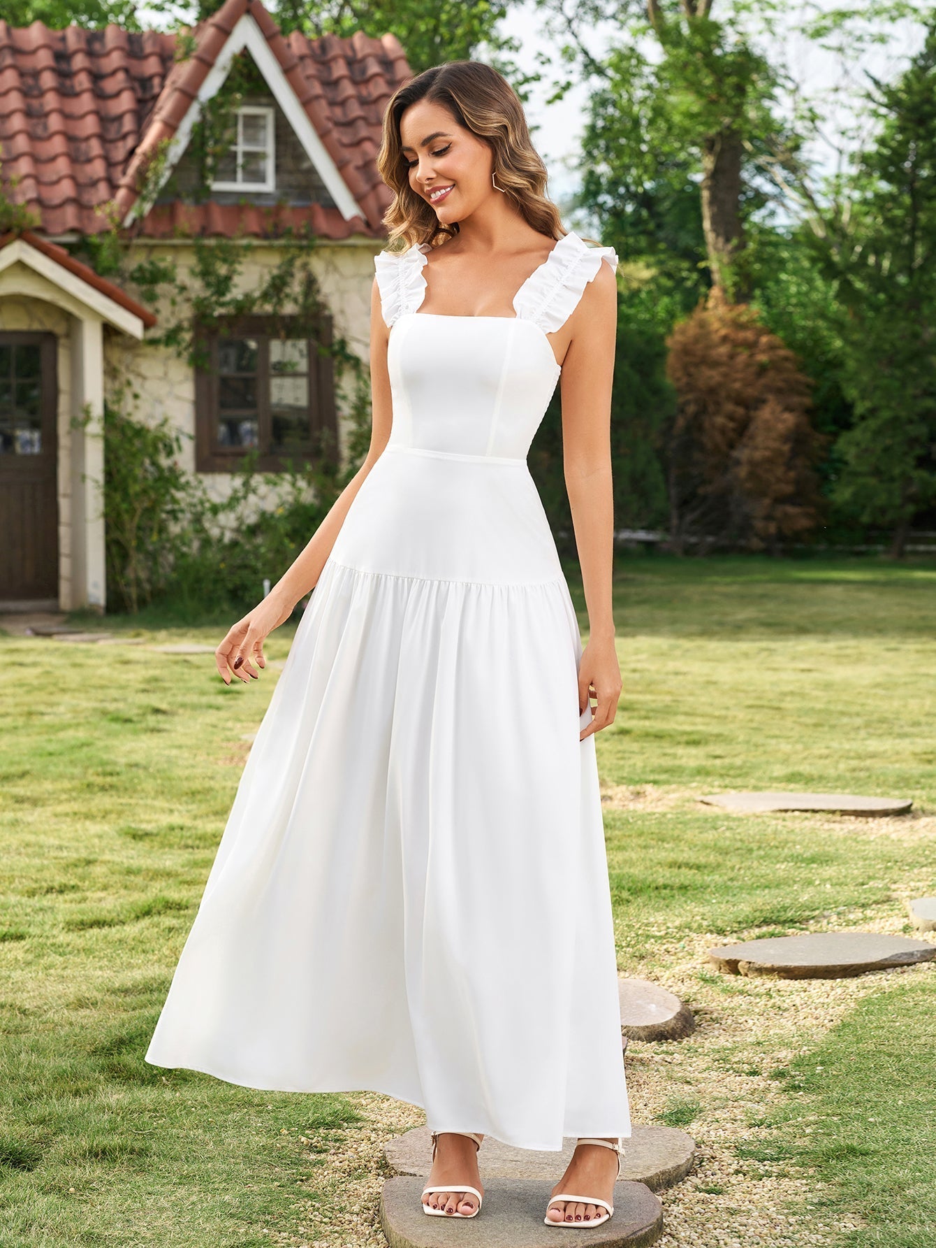 Full-length shot of a woman in a white midi dress with ruffled straps and a tiered skirt, posing outdoors.