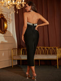 Woman in a black outfit with a beaded waistband in an elegant room with chandelier and gold bench.