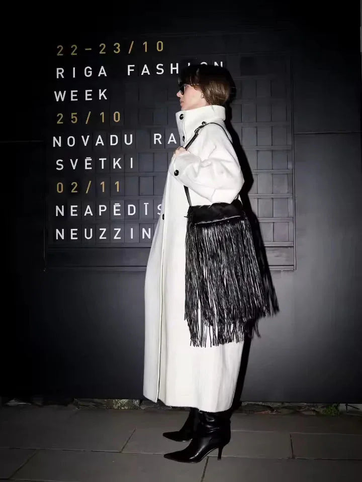 Close-up of the funnel neck and button detail on a white wool blend coat