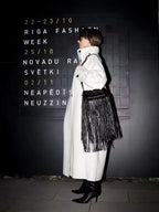 Close-up of the funnel neck and button detail on a white wool blend coat