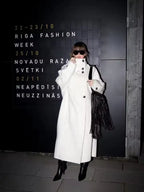 Side profile of a woman in a long white wool blend coat