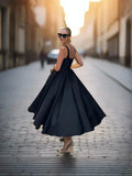 Woman in a black fit and flare dress with a square neckline, seen from the back, showcasing the voluminous skirt.