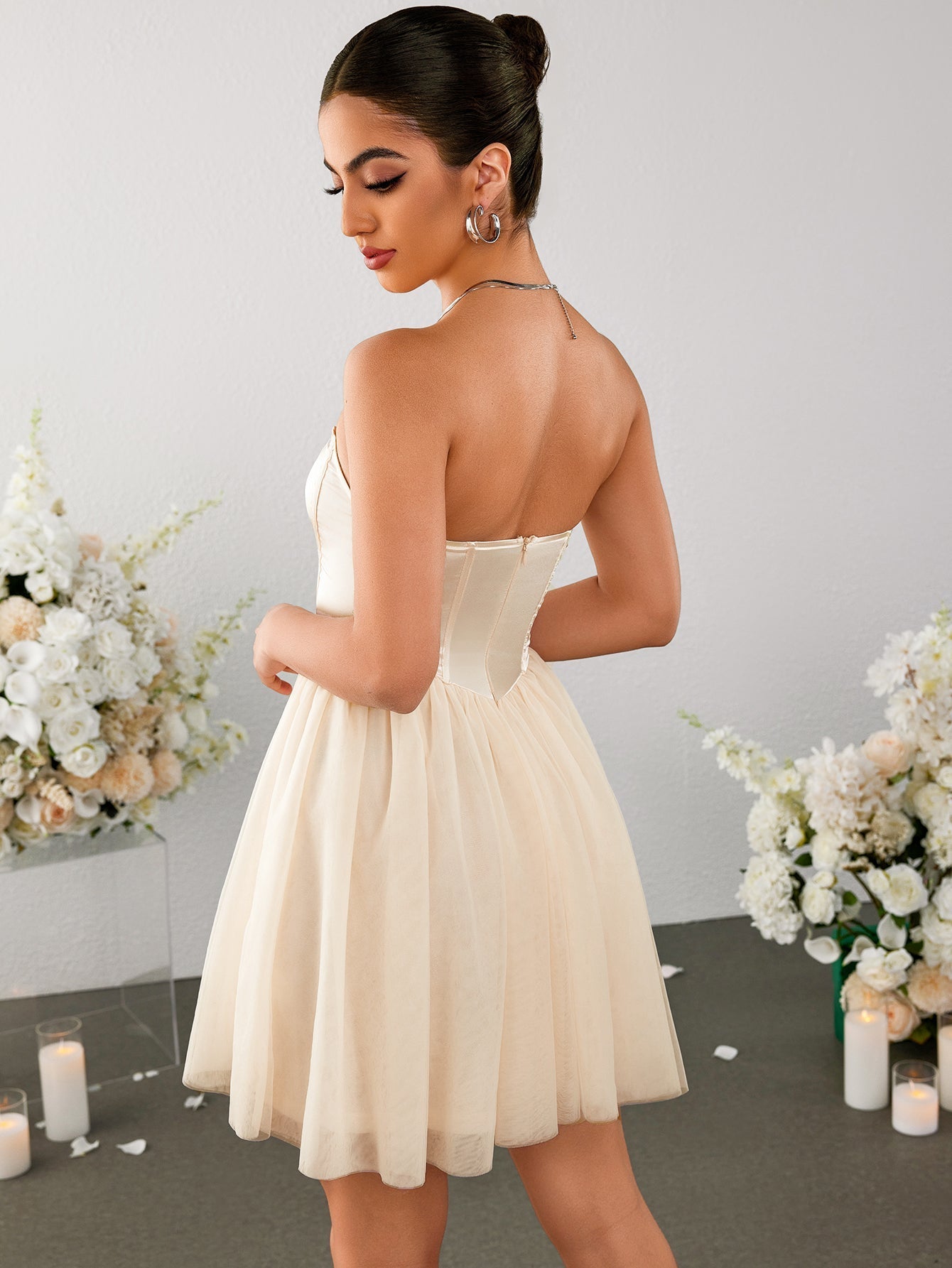 Back view of a woman in an ivory strapless corset bodice mini dress with a tulle skirt