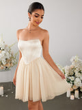 Woman in an ivory strapless corset bodice mini dress with a tulle skirt, looking down and holding the skirt