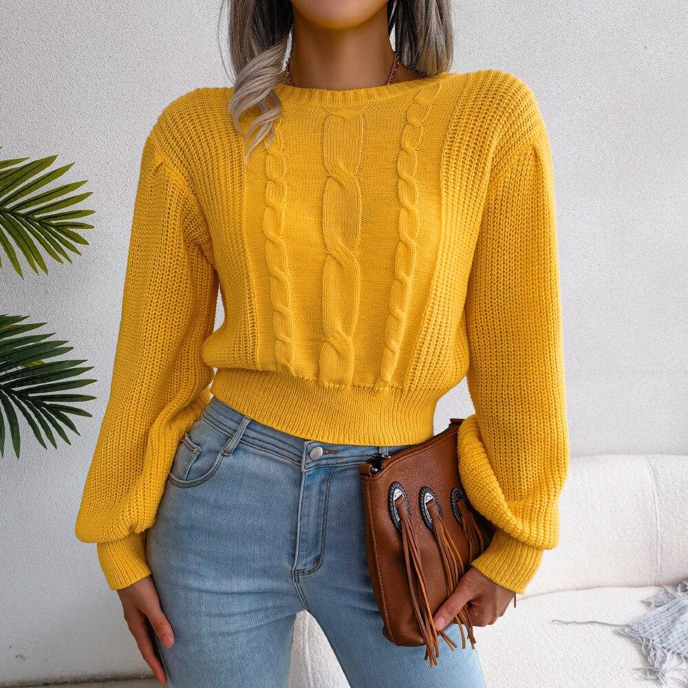 Woman wearing a yellow cable knit cropped sweater with balloon sleeves and light wash jeans.