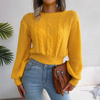 Woman wearing a yellow cable knit cropped sweater with balloon sleeves and light wash jeans.