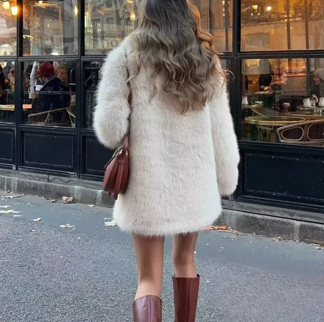 Back view of a woman wearing a cream faux fur coat with a notch lapel and long sleeves.
