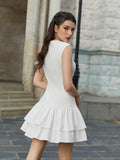 Back view of a woman in a white sleeveless crepe mini dress with a ruffled hem