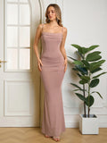 Woman wearing a long, taupe, spaghetti strap, ruched mermaid dress with a cowl neckline, posing with hands at sides.