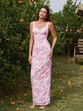 Full body shot of a woman wearing a long white and pink floral print column dress with tank straps and a scoop neckline, standing in a garden setting.
