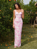 Front view of a woman in a long white and pink floral print column dress with tank straps and a scoop neckline, posing outdoors.