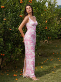 Side view of a woman in a long white and pink floral print column dress with tank straps and a scoop neckline, standing outdoors.