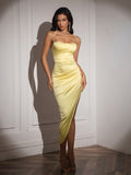 Full-length view of a woman in a yellow satin bodycon dress with a cowl neckline and spaghetti straps, showcasing the ruched detailing.