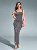 Woman in a floor-length silver sequined gown with a square neckline, holding a clutch bag and posing against a grey backdrop.