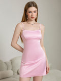 Model posing in a pink satin mini dress with spaghetti straps