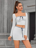 Front view of a woman in a white ribbed knit two-piece set with a cropped top and bodycon skirt.