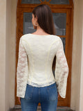 Back view of a woman in a cream lace top with bell sleeves and blue jeans