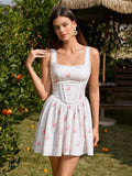 Woman wearing a white floral print sleeveless mini dress with a square neckline and lace trim standing outdoors by an orange tree.