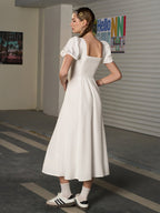 Back view of a woman in a white A-line midi dress with a smocked back.