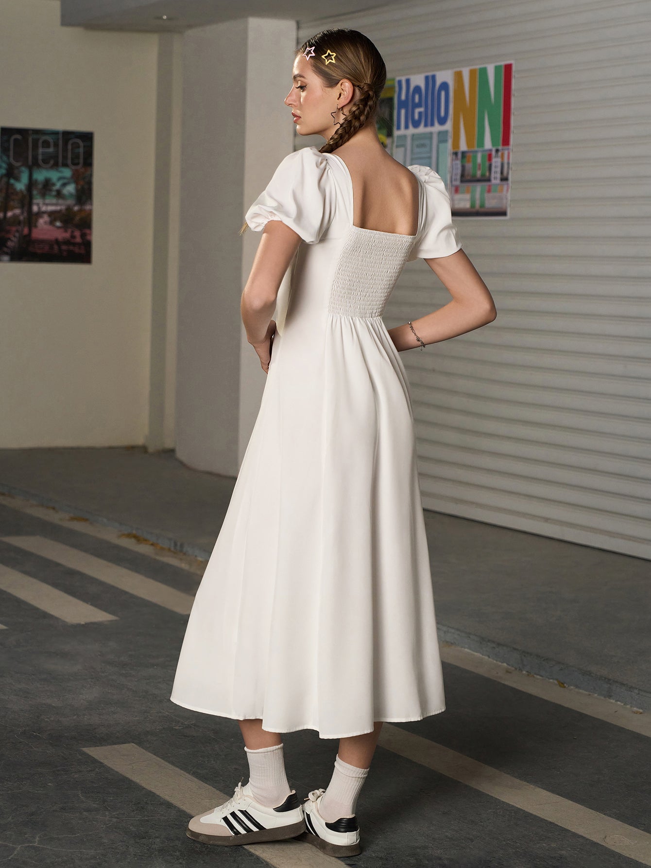 Back view of a woman in a white A-line midi dress with a smocked back.