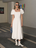 Woman wearing a white square neck puff sleeve midi dress.
