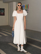 Woman wearing a white square neck puff sleeve midi dress.