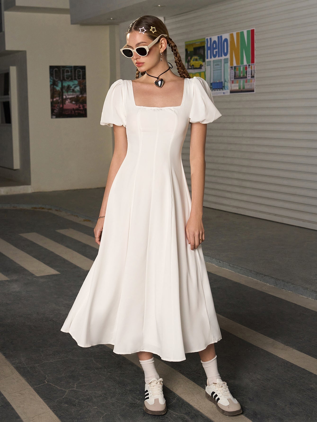 Woman posing in a white midi dress with puff sleeves and an A-line skirt.